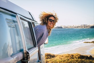 Smiling woman leaning out of camper van by beach in Fuerteventura