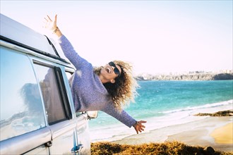 Woman leaning out of camper van window by beach in Fuerteventura