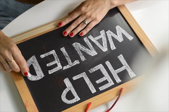 Woman writing 'Help Wanted' on chalkboard