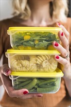 Woman holding stack of food in plastic containers