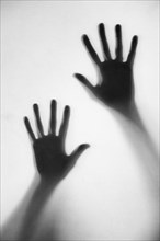 Silhouette of woman's hands touching frosted glass