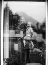 Father holding his daughter behind window