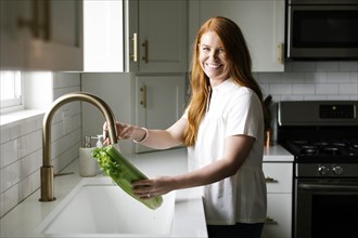 Woman washing celery in kitchen sink