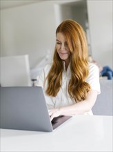 Redheaded woman using laptop at home