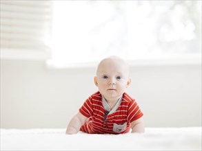 Baby boy wearing striped romper on bed