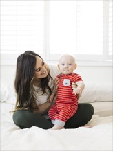 Smiling woman holding her son on bed