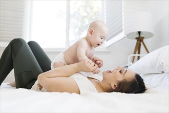 Mother playing with her son on bed