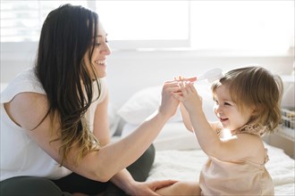 Mother and daughter on bed with hairbrush