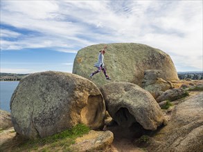 Woman jumping on boulders on Granite Island, Australia