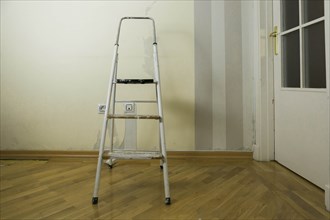 Step ladder by wall of torn wallpaper