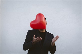 Man throwing red heart shaped balloon