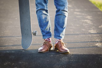 Feet of man with skateboard on footpath