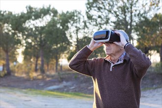 Senior man wearing virtual reality simulator outdoors