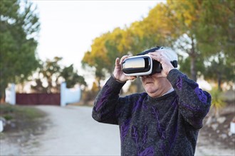 Senior man wearing virtual reality simulator outdoors