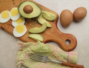 Avocado, egg and sunflower seeds on cutting board