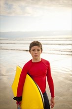 Boy holding body board on beach