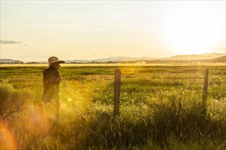 Farmer by fence at sunset in Picabo, Idaho, USA