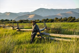 Farmer leaning on fence in Picabo, Idaho, USA