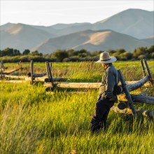 Farmer leaning on fence in Picabo, Idaho, USA