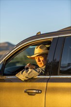 Farmer wearing cowboy hat driving SUV