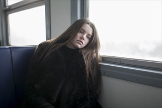 Young woman wearing black fur coat on train