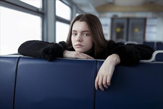 Young woman leaning on blue seat on train