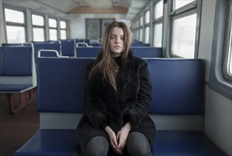 Young woman wearing black fur coat on train