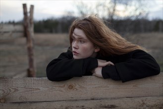 Teenage girl leaning on wooden fence