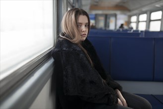 Young woman wearing black fur coat on train