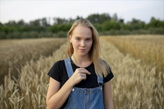 Smiling young woman holding wheat in field