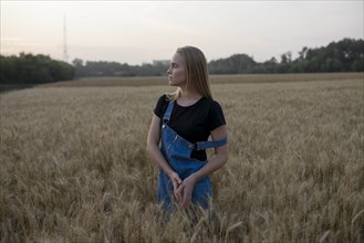 Young woman wearing overalls in wheat field