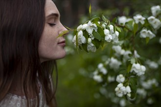 Young woman with her eyes closed sniffing flowers