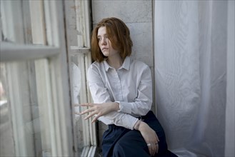 Young woman wearing white shirt on window sill