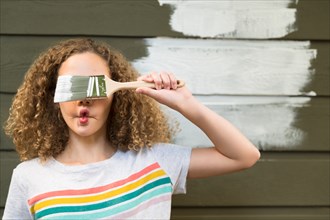Girl covering her eyes with paint brush