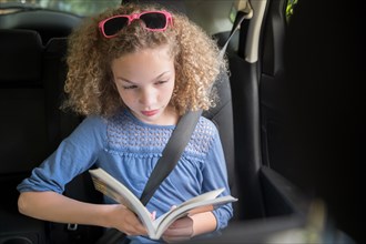 Girl reading book in car