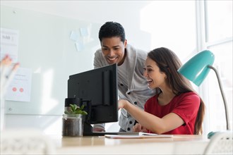 Coworkers smiling at computer together