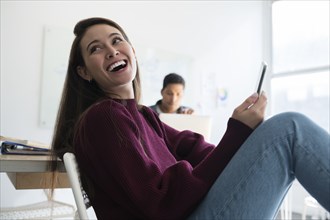 Smiling woman holding smartphone in office