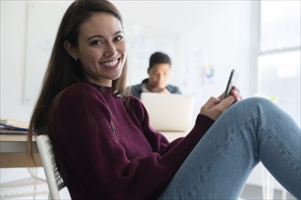 Smiling woman holding smartphone in office