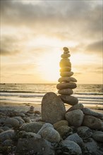 Stacked stones on beach at sunset