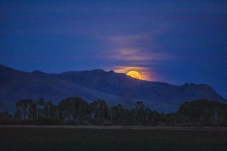 Full moon behind mountain in Bellevue, Idaho, USA
