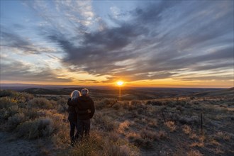 Couple in field at sunset at Boise Foothills in Boise, Idaho, USA