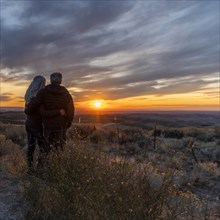 Couple in field at sunset at Boise Foothills in Boise, Idaho, USA