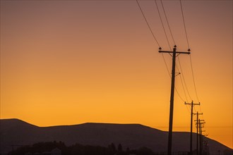 Silhouette of power lines and hill at sunset in Picabo, Idaho, USA