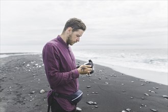 Man holding camera on beach in Iceland