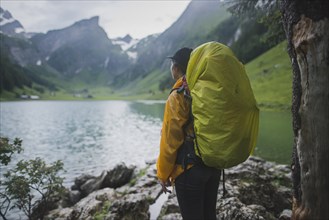 Woman wearing yellow backpack by Seealpsee lake in Appenzell Alps, Switzerland