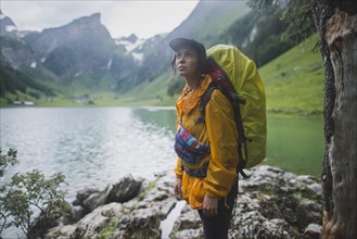 Woman wearing yellow backpack by Seealpsee lake in Appenzell Alps, Switzerland