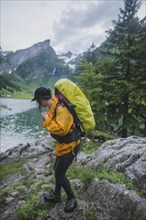 Woman wearing yellow hiking by Seealpsee lake in Appenzell Alps, Switzerland