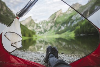 Woman's feet sticking out of tent by Seealpsee lake in Appenzell Alps, Switzerland