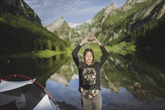 Woman making heart hand sign by Seealpsee lake in Appenzell Alps, Switzerland