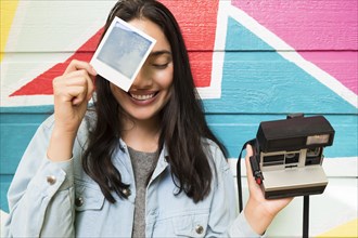 Smiling woman holding photograph and Polaroid camera